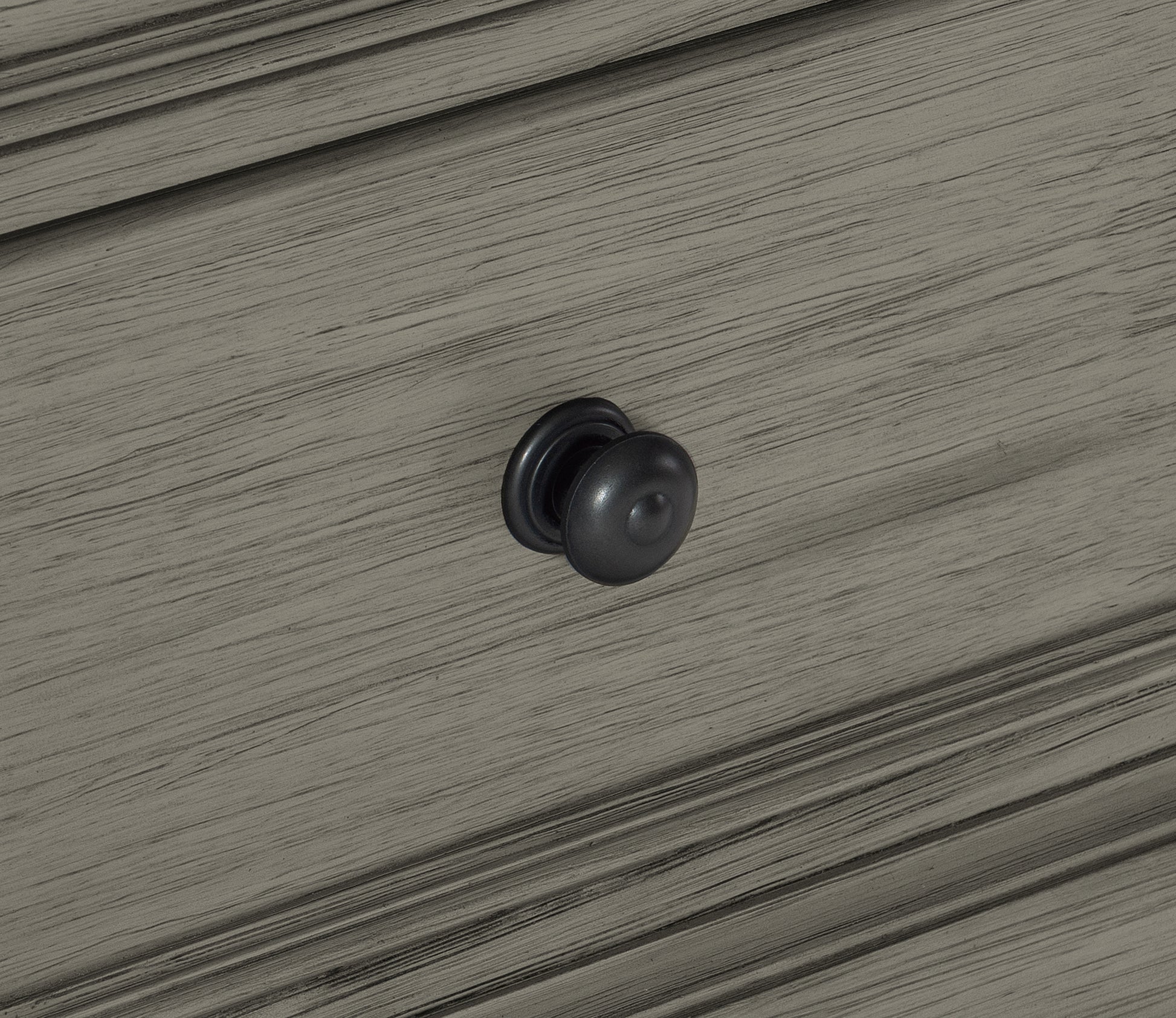 Dark charcoal round drawer knob on distressed grey wood cabinet