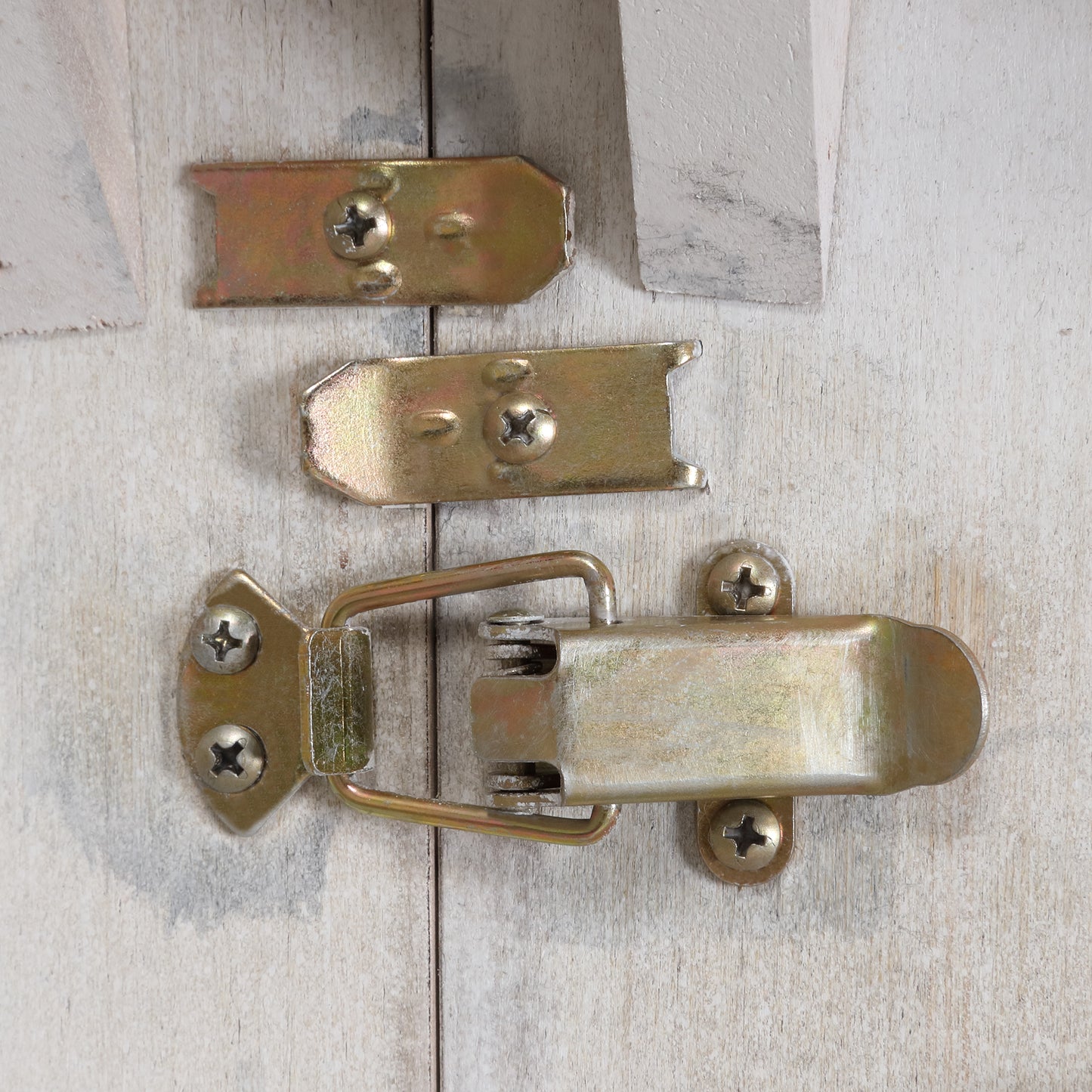 Golden metal clasp with latch and screws on distressed wood