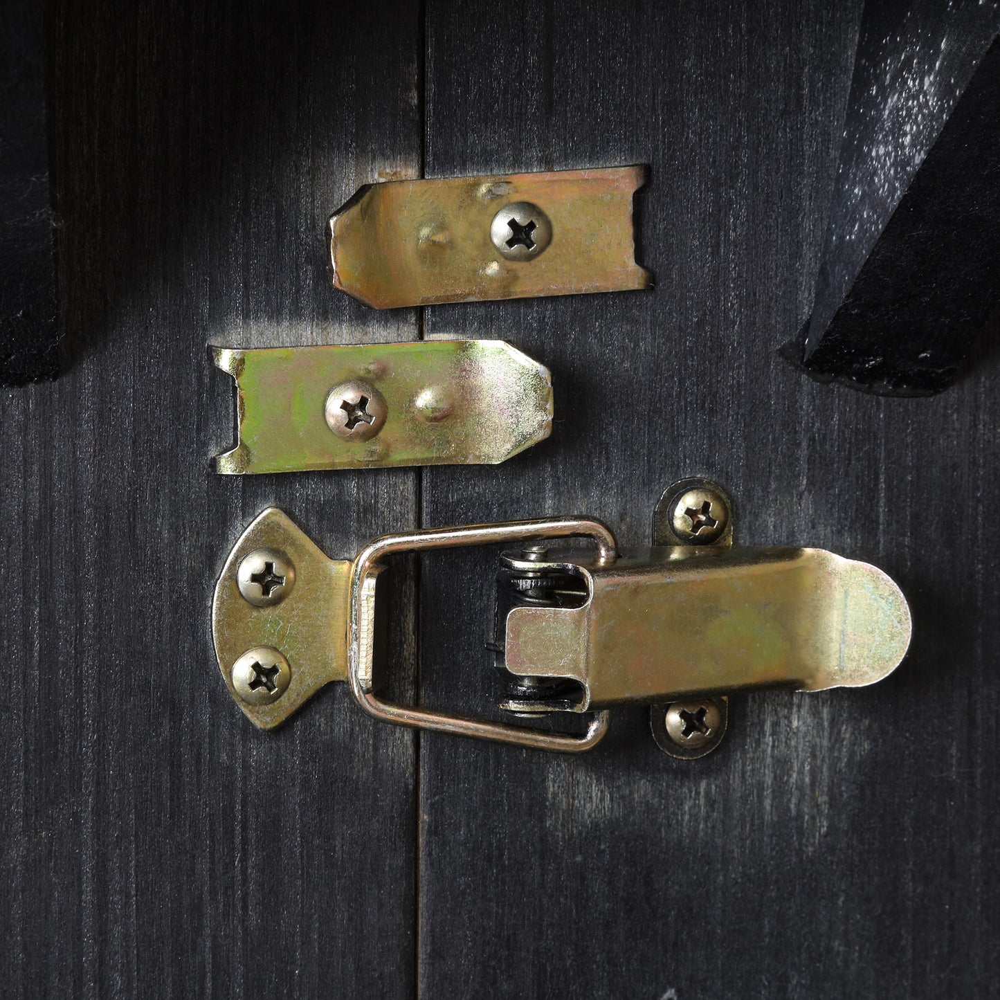 Gold metal latch set with screws on distressed black wood