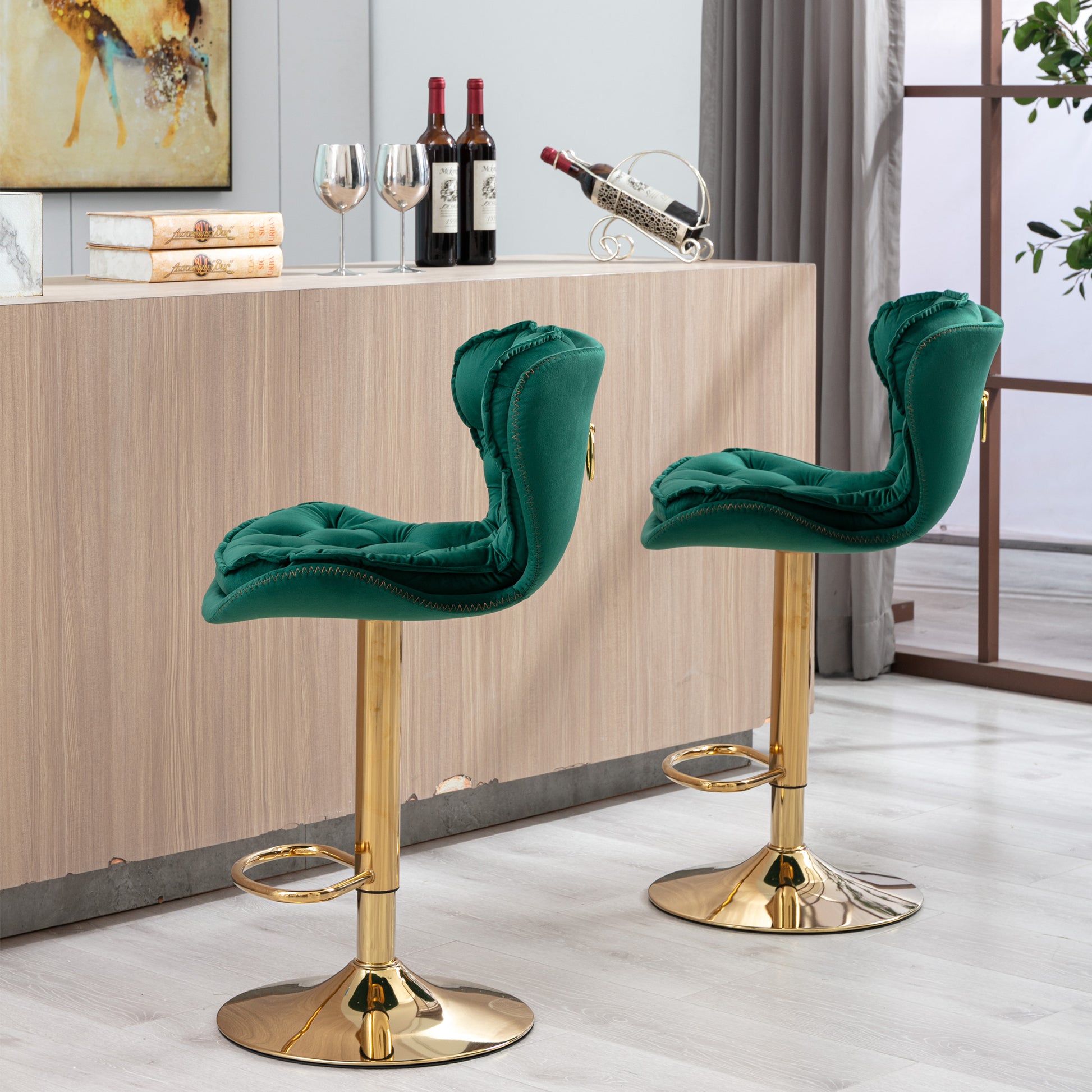 Two emerald green velvet bar stools with tufted seats and gold bases