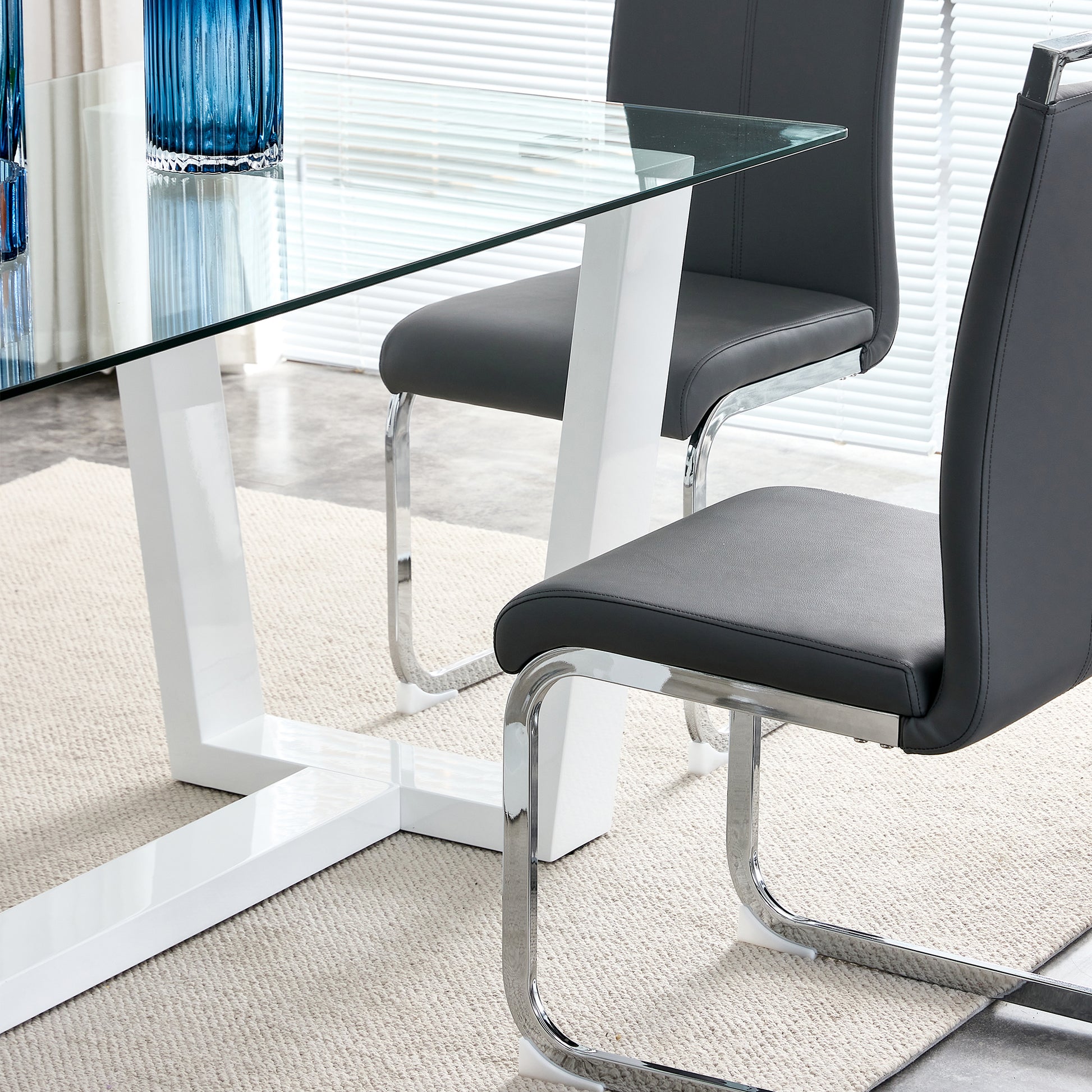 Glass top dining table with modern white pedestal base and grey faux leather chairs