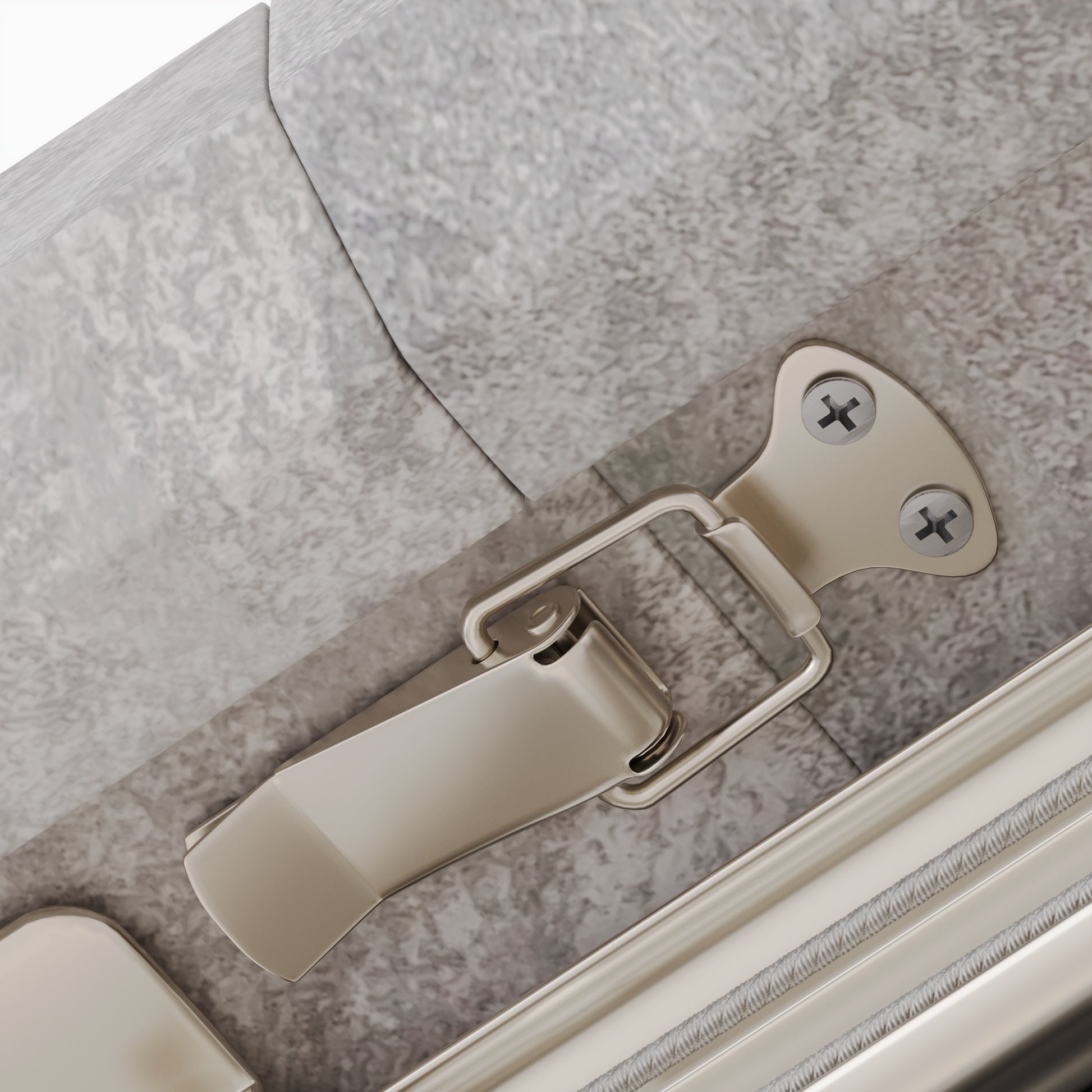Brushed nickel suitcase latch with silver screws on a gray textured surface