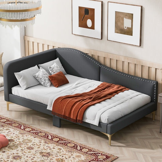Dark gray velvet daybed with nailhead trim and gold legs featuring an orange throw