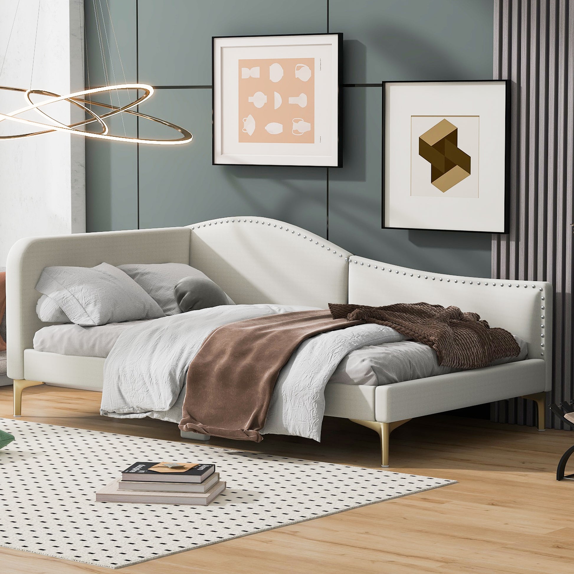 Cream upholstered daybed with gold legs and silver nailhead trim