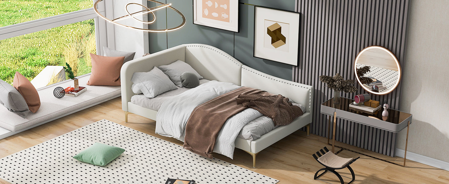 White upholstered daybed with gold legs and scattered pillows