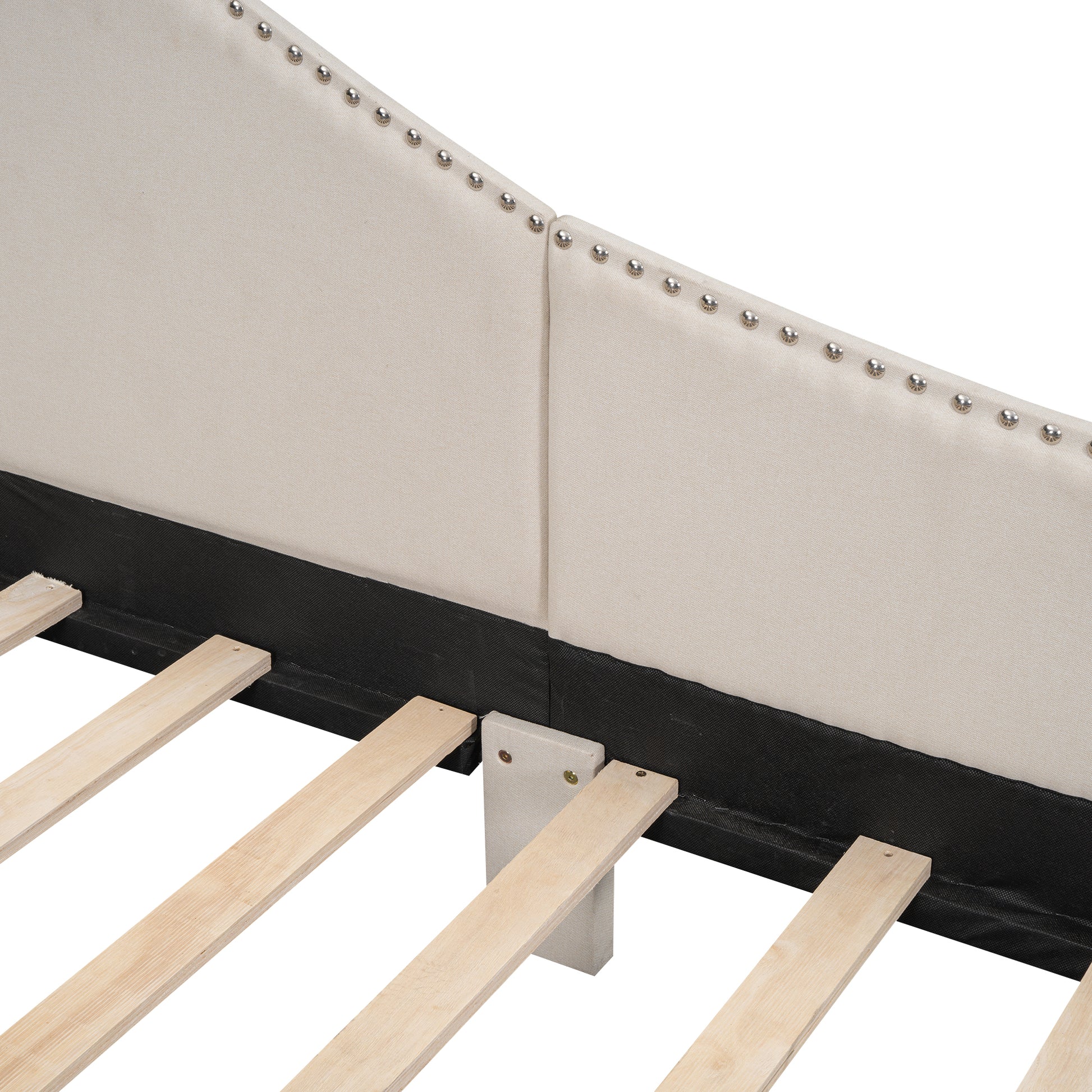 Upholstered beige headboard detail with silver nailhead trim and wooden slats