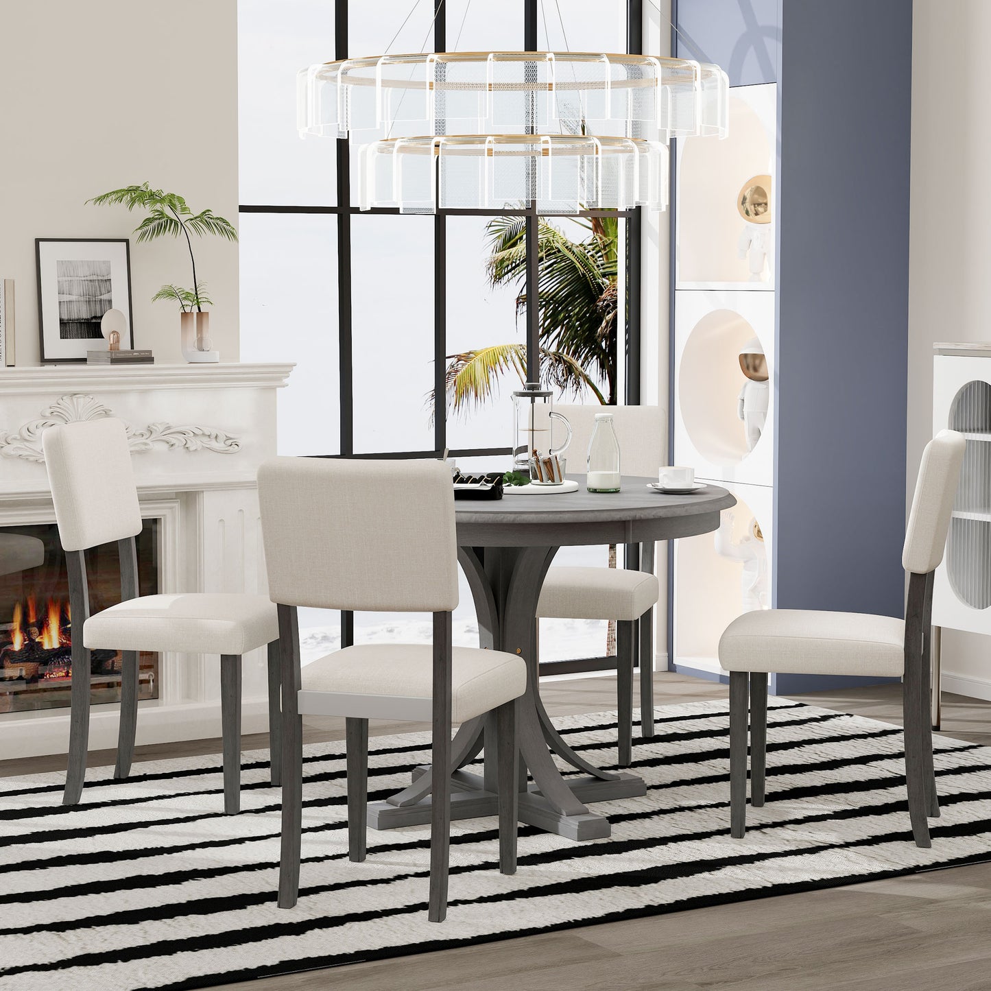 Round grey pedestal dining table with four cream upholstered chairs