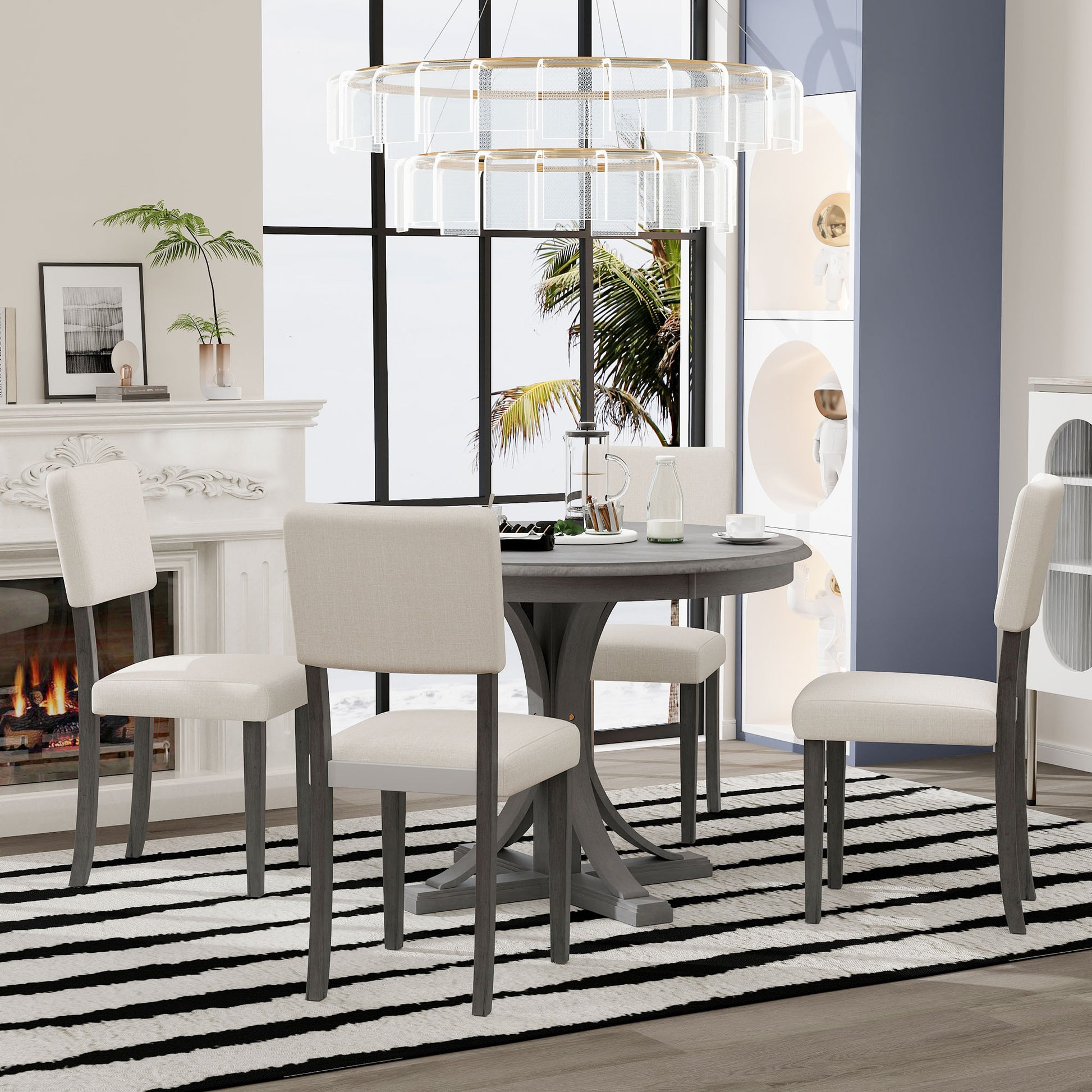 Round grey pedestal dining table with four cream upholstered chairs