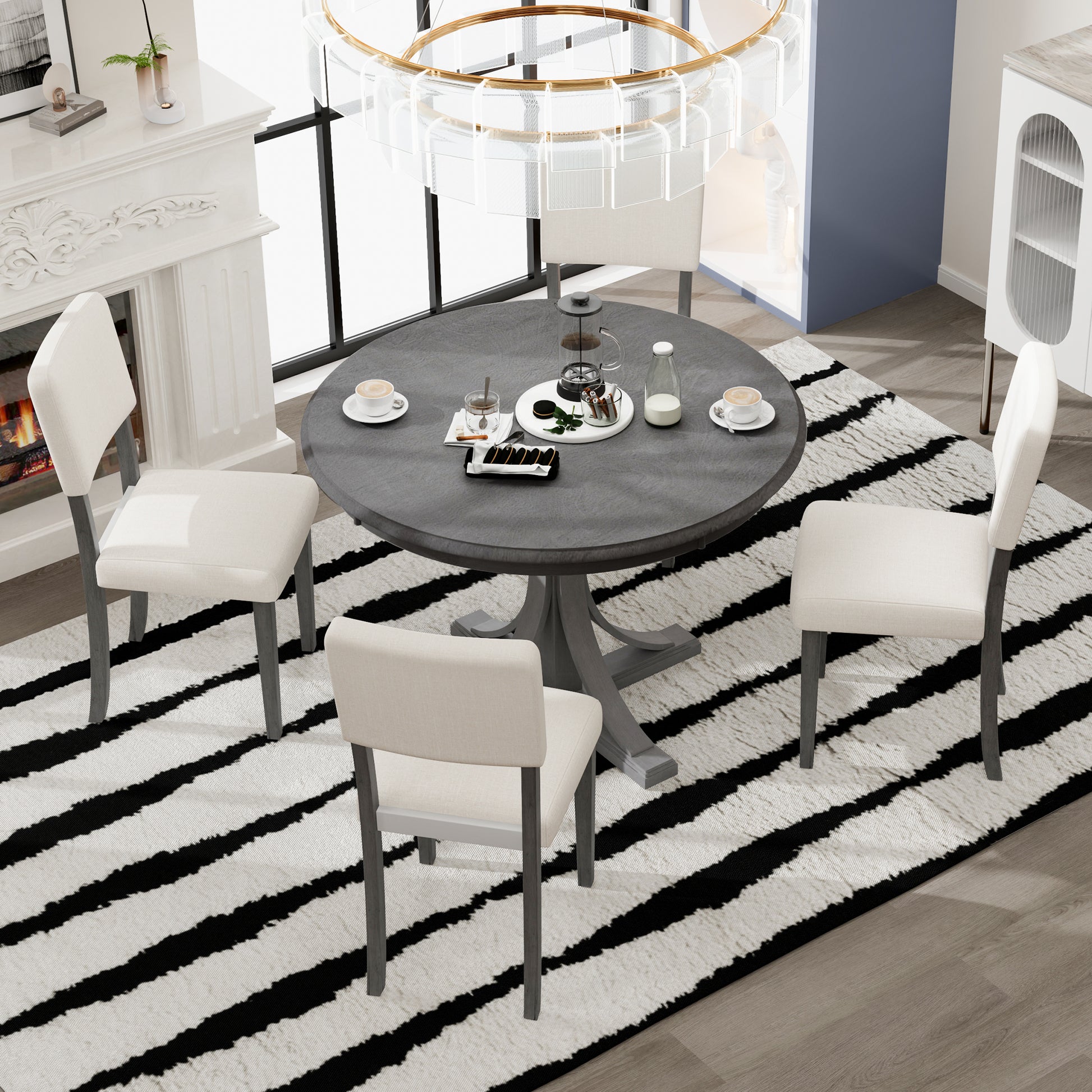 Round gray pedestal dining table with four cream upholstered chairs
