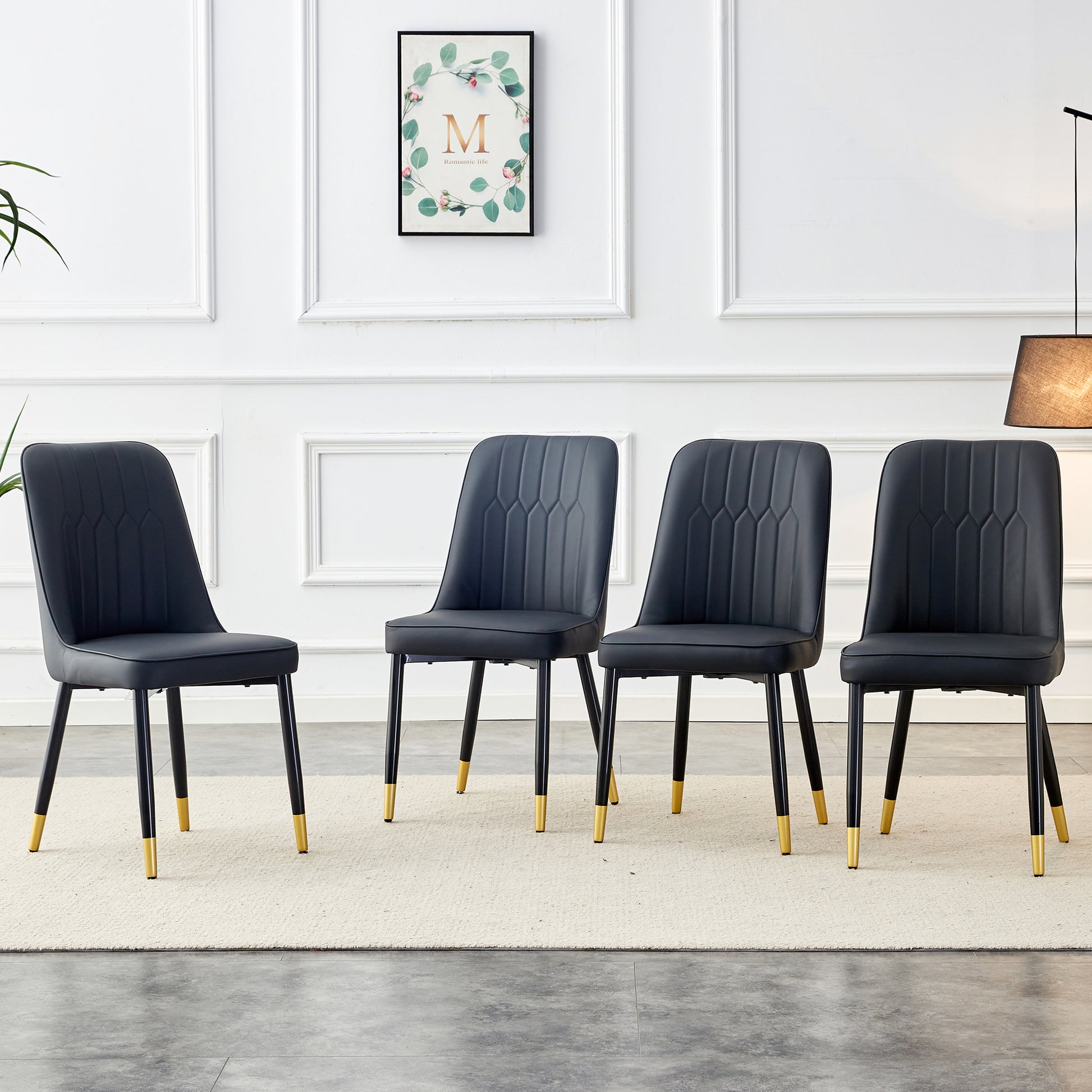 Four black faux leather dining chairs with goldtipped legs