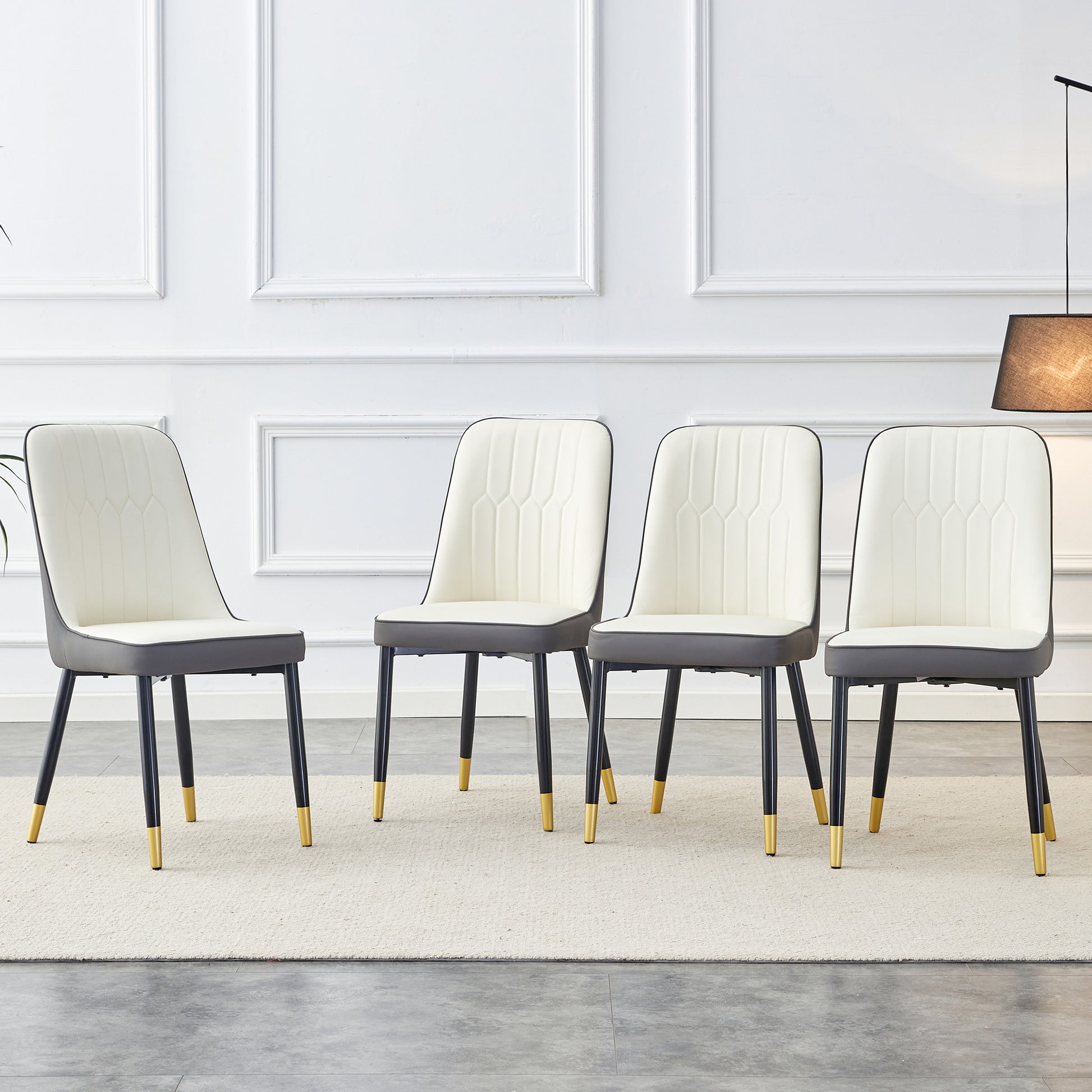 Four cream and gray upholstered dining chairs with goldtipped black legs
