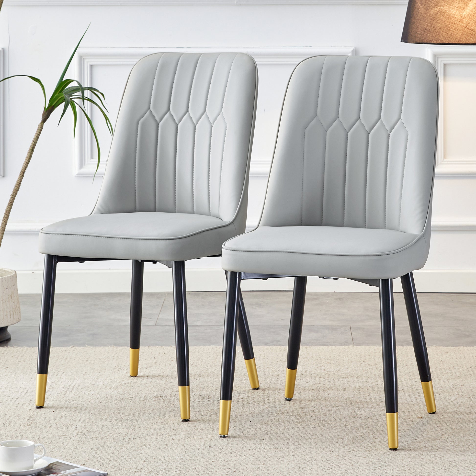 Light gray faux leather dining chair with vertical stitching and goldtipped black legs