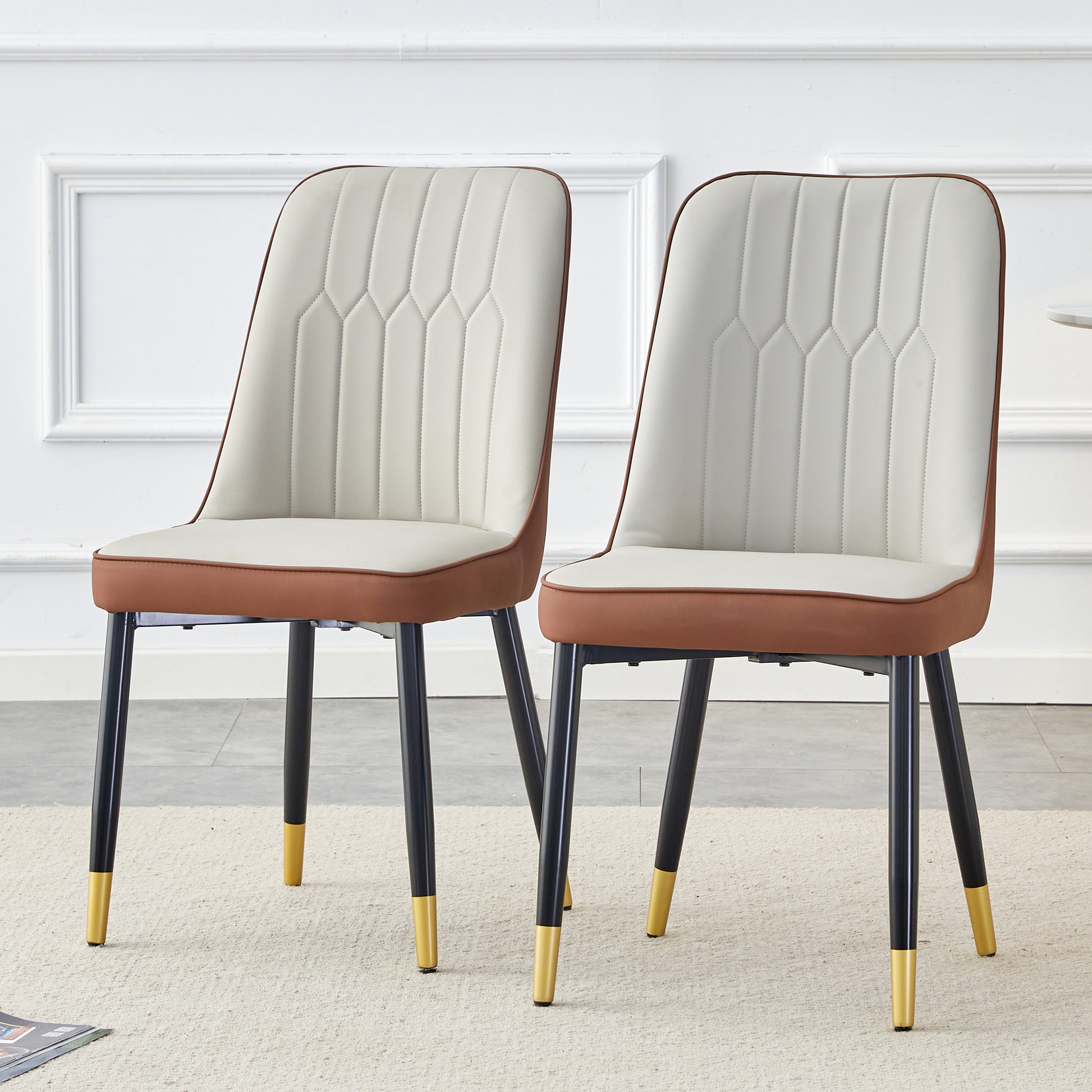 Cream and tan upholstered dining chair with stitched detailing and goldtipped black legs