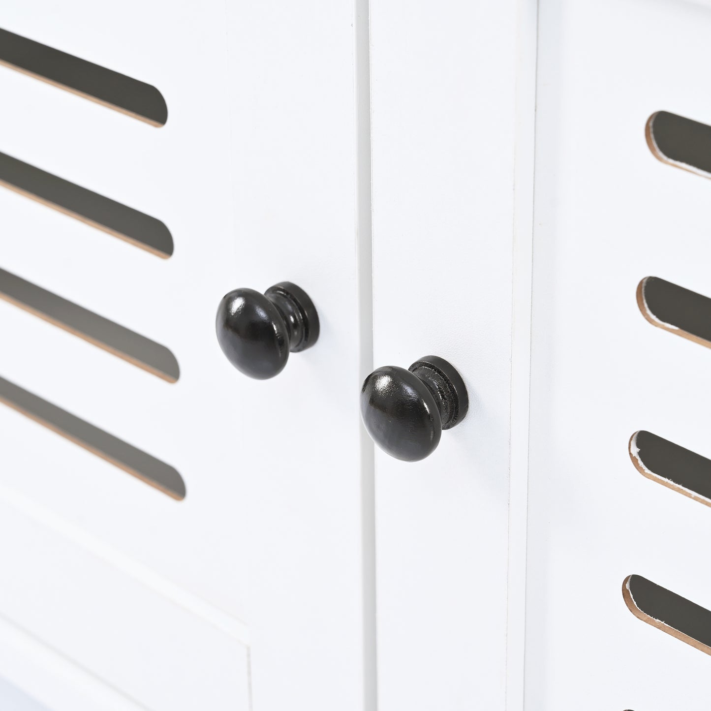 White cabinet door with black oval knobs and slatted detail