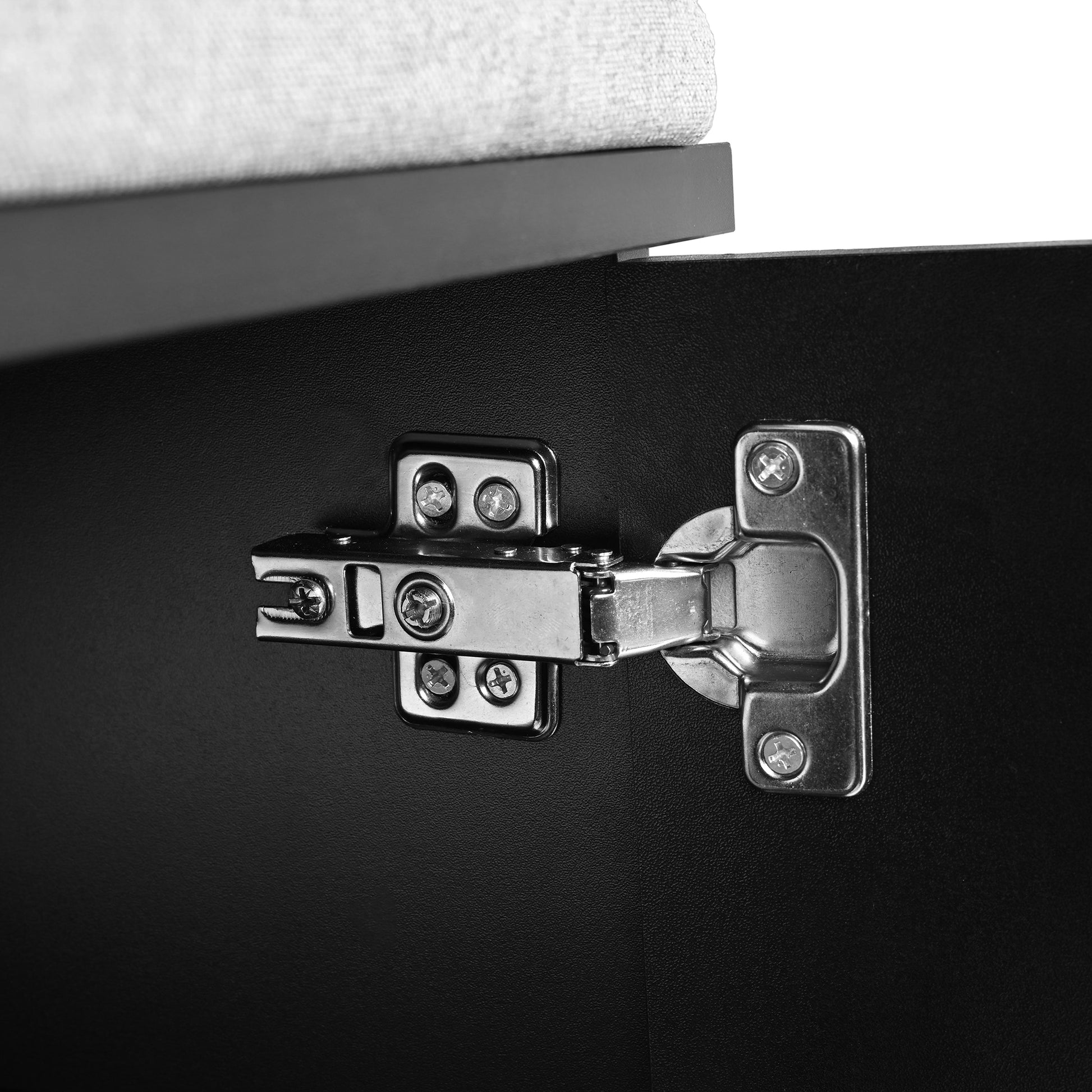 Closeup of silver cabinet hinge on black textured surface