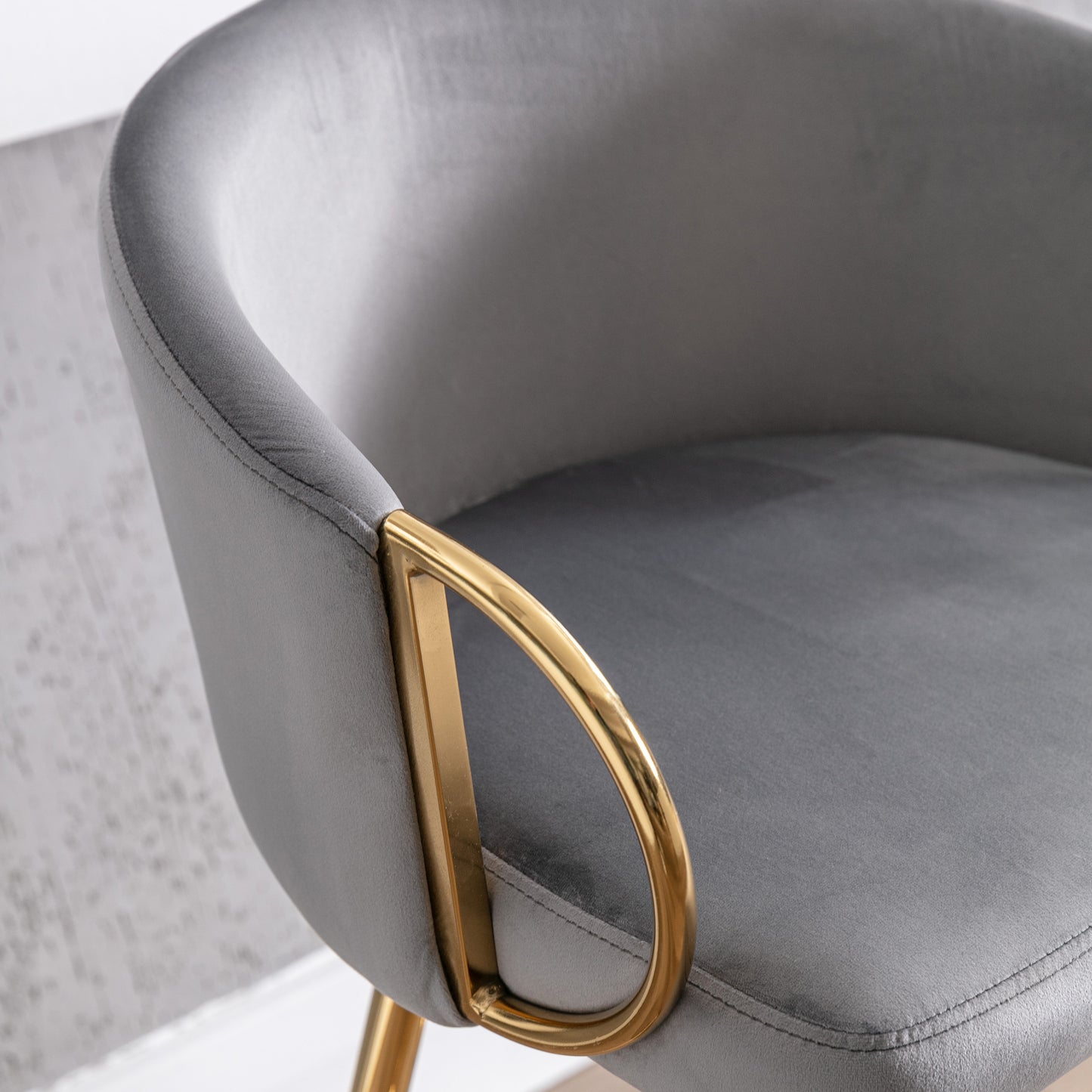Close up of gray velvet armchair armrest with gold metal accent