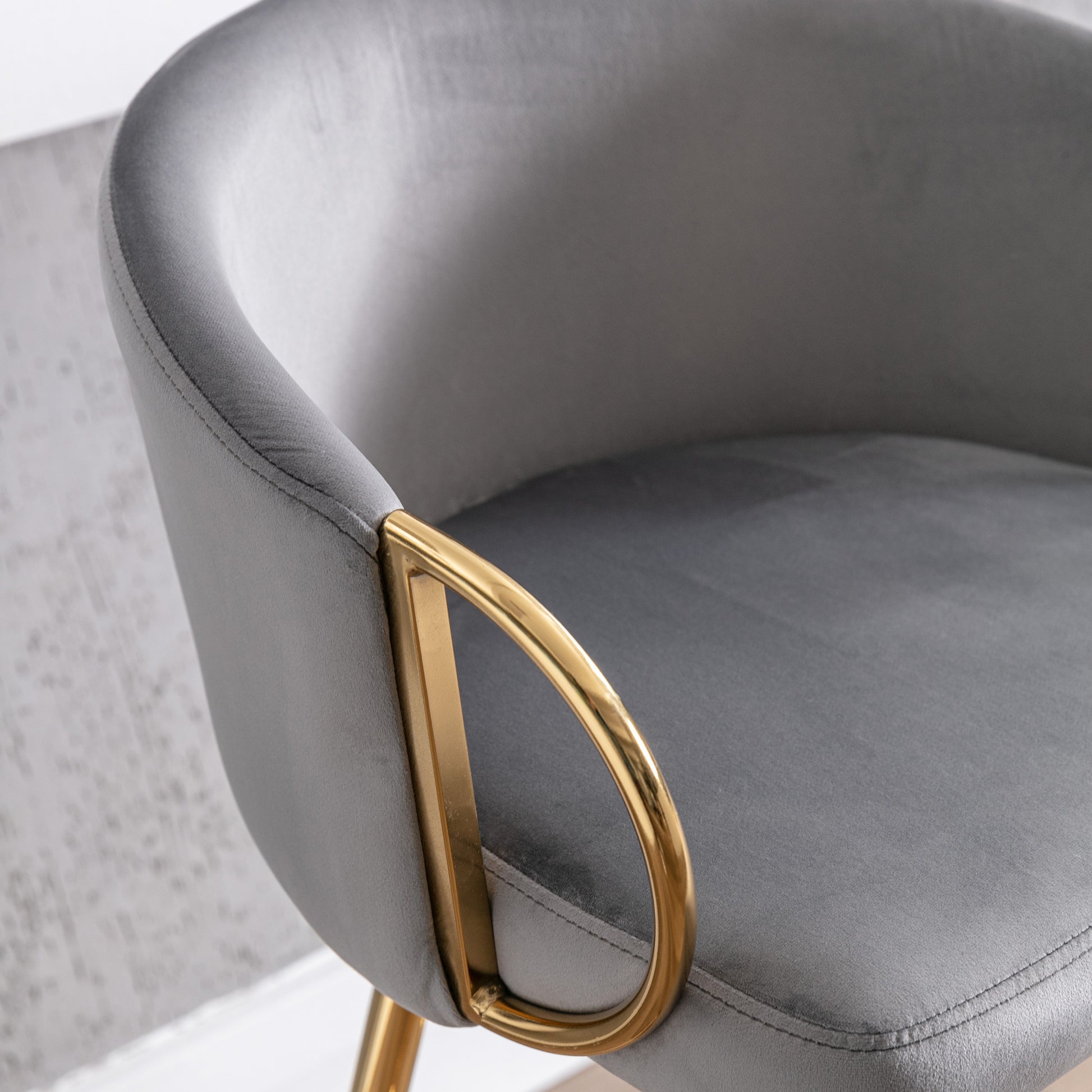 Close up of gray velvet armchair armrest with gold metal accent
