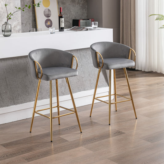 Two grey velvet bar stools with gold metal legs and armrests in a modern home setting