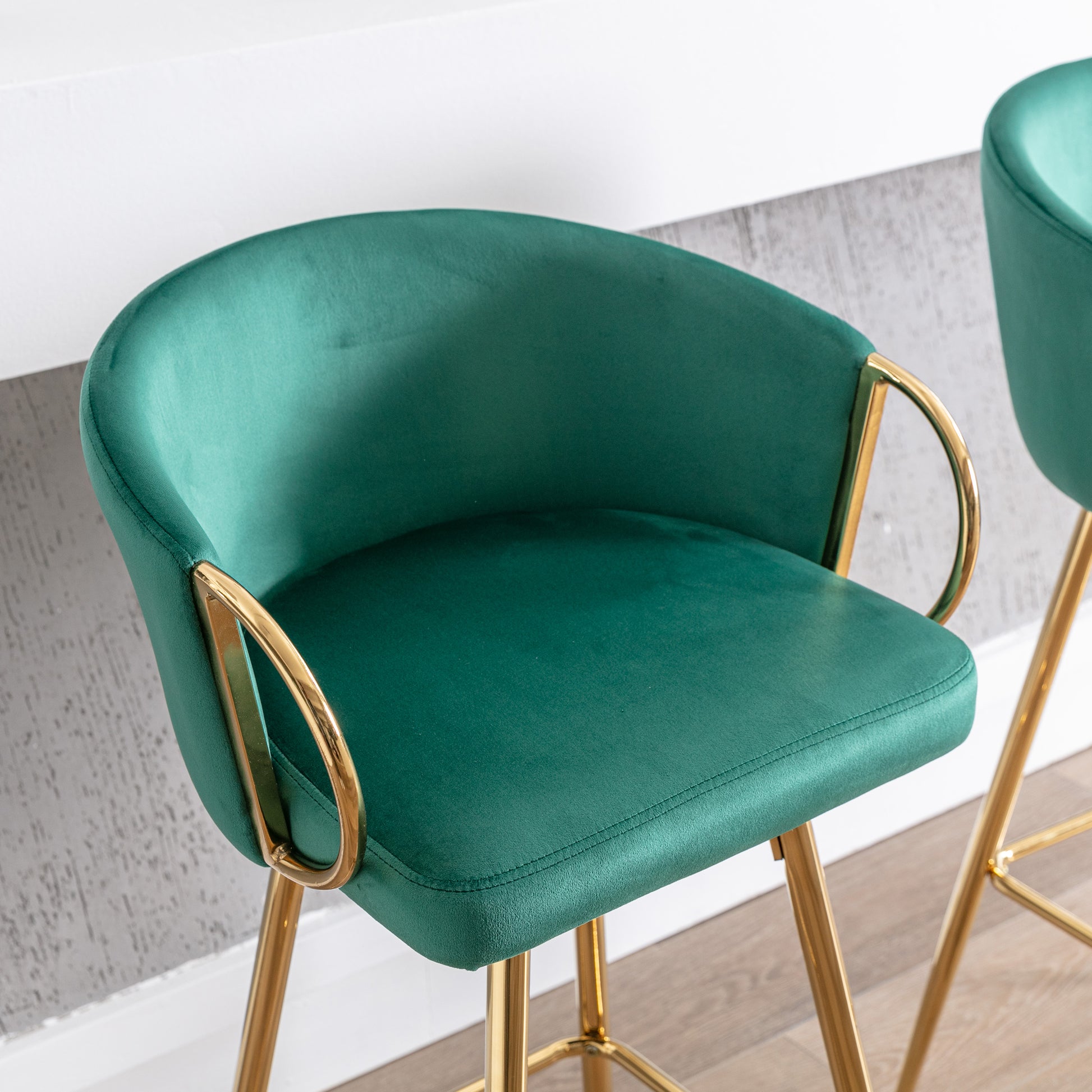 Emerald green velvet bar stool with gold legs and curved armrests