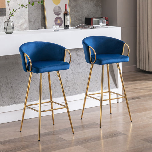 Two plush navy blue velvet bar stools with gold legs