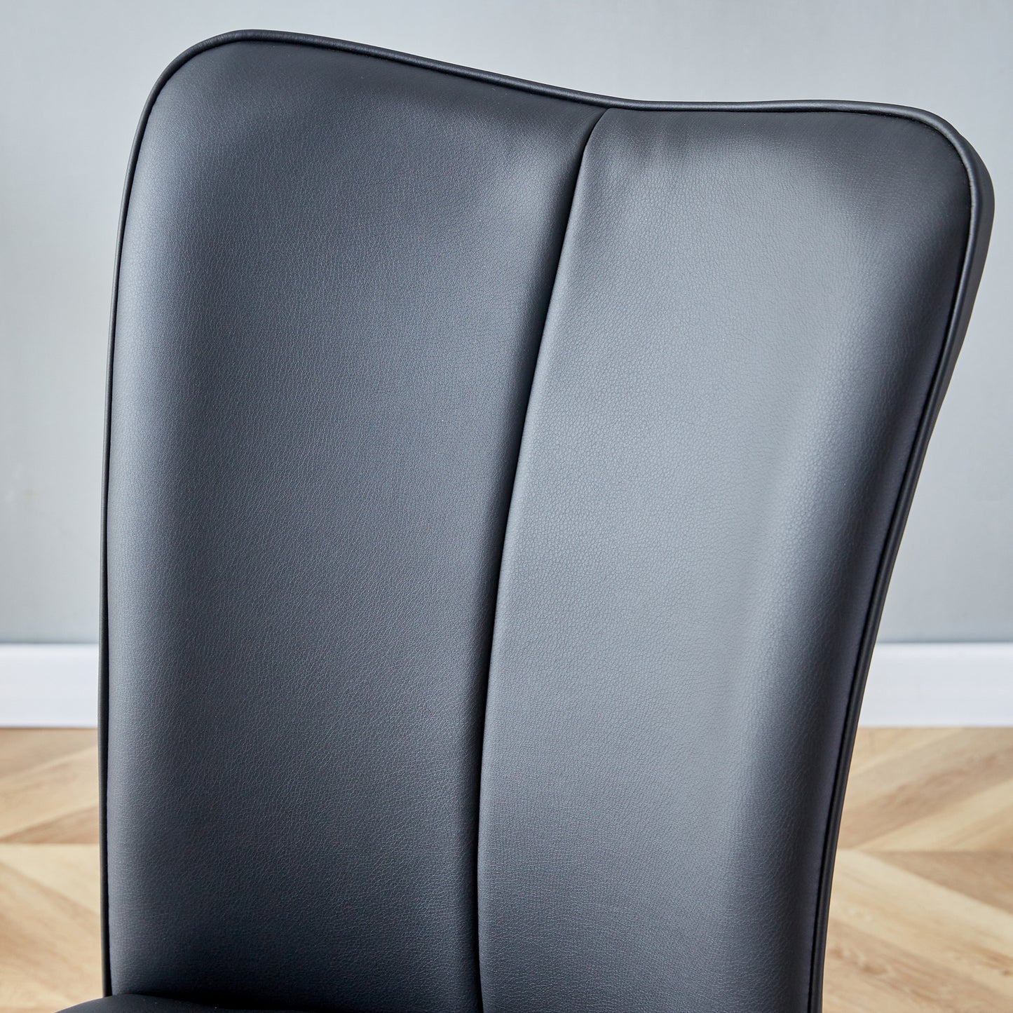 Black faux leather dining chair back with contoured stitching for modern style