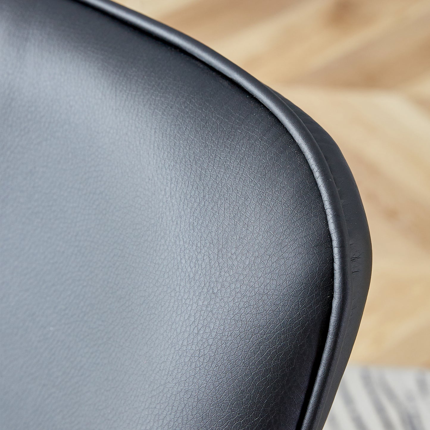 Black faux leather chair back detail with stitched edge