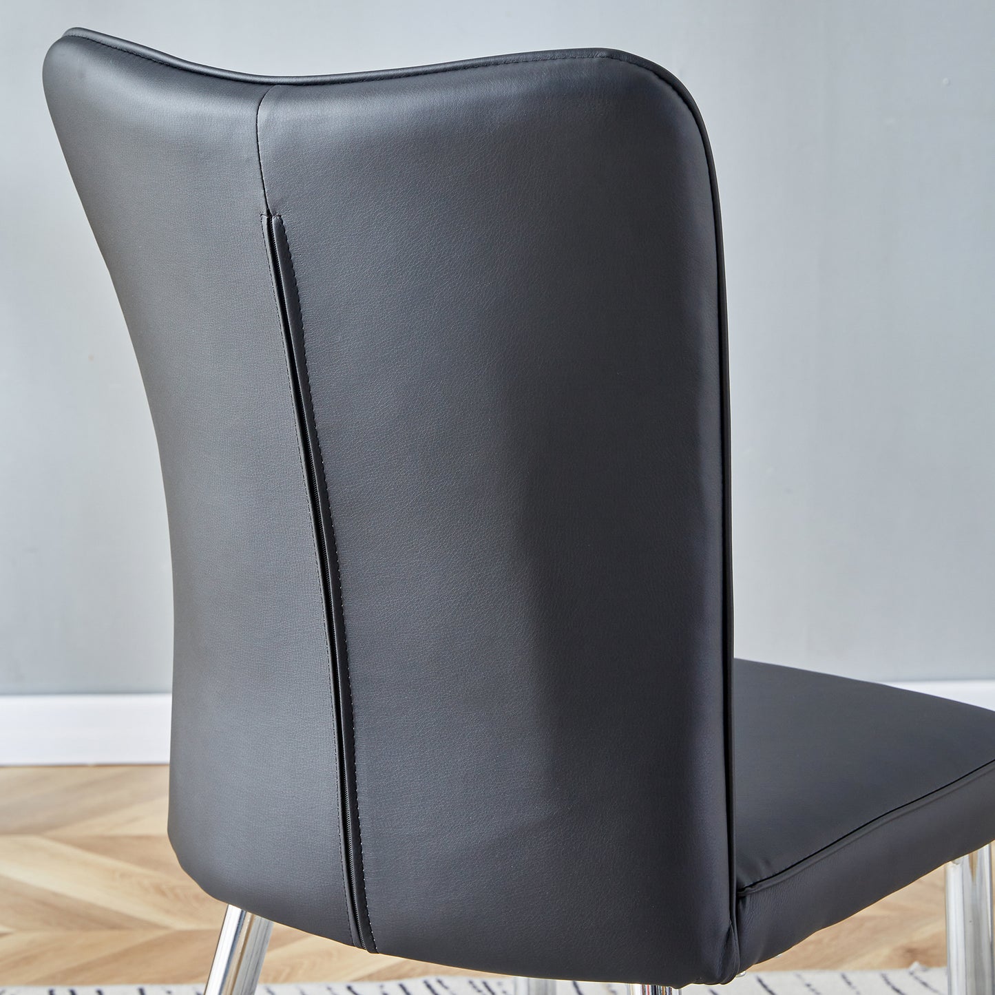 Closeup of black faux leather dining chair back with silver legs