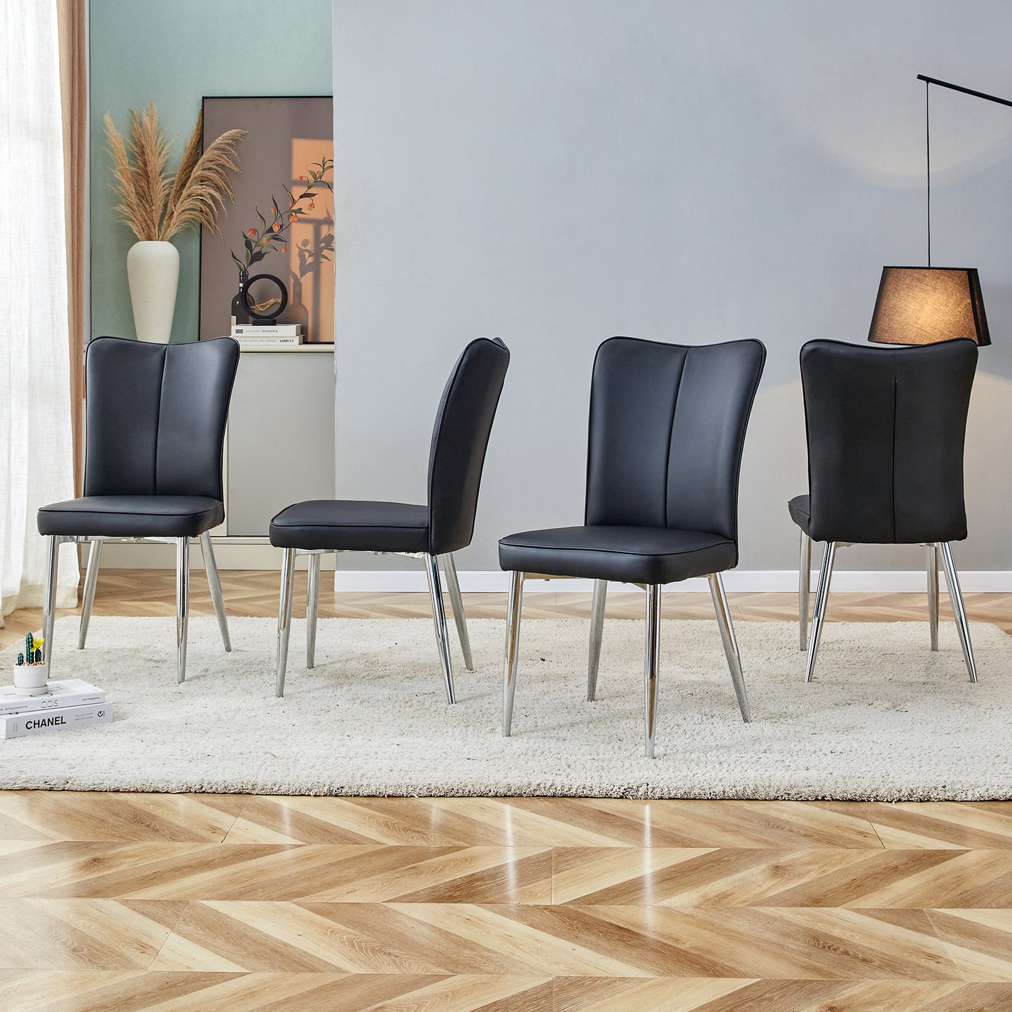 Four black leather dining chairs with chrome legs arranged on a rug