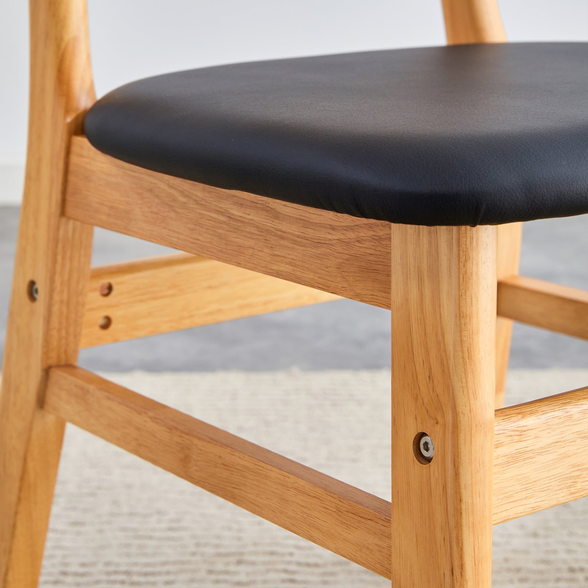 Close up of a black faux leather seat on a solid wood dining chair