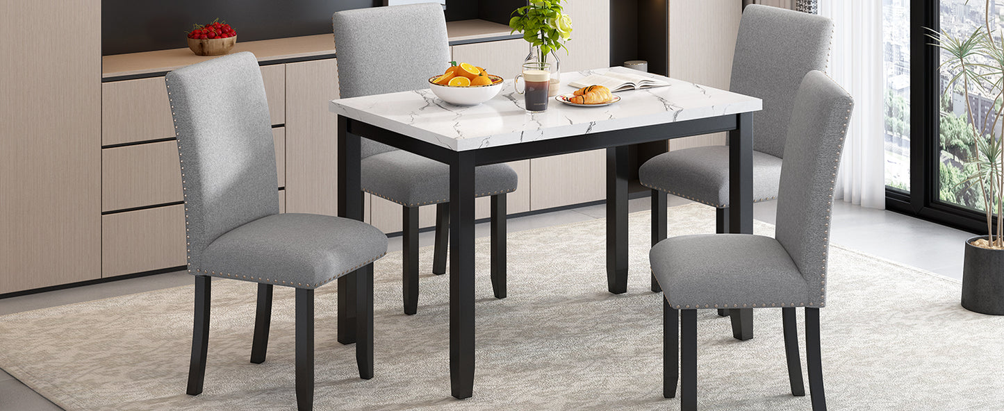 Grey upholstered dining chairs with silver nailhead trim around a marbletop table