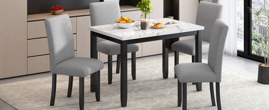 Grey upholstered dining chairs with silver nailhead trim around a marbletop table