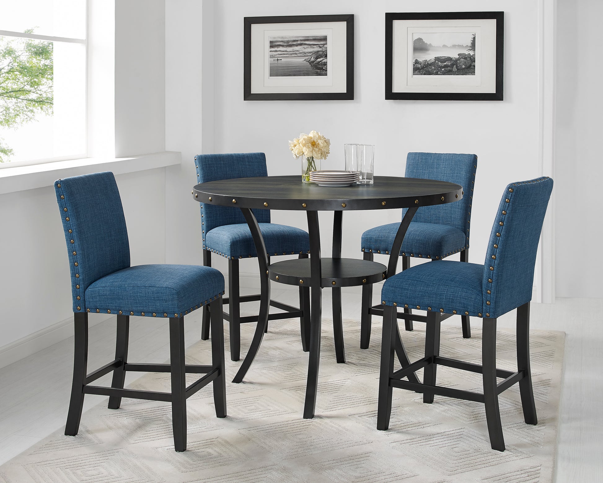Round dark wood counter height table with riveted edge and four blue upholstered bar stools
