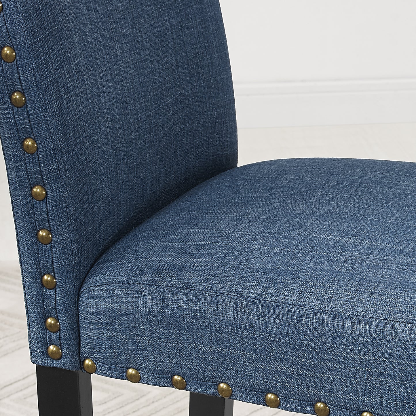 Closeup of blue upholstered dining chair with brass nailhead trim
