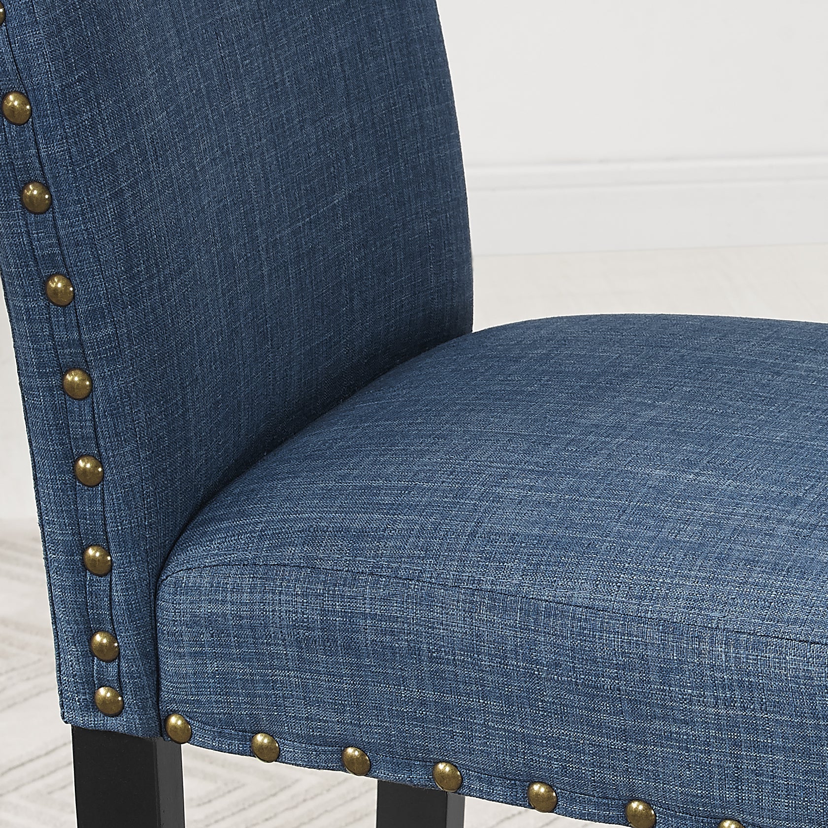 Closeup of blue upholstered dining chair with brass nailhead trim