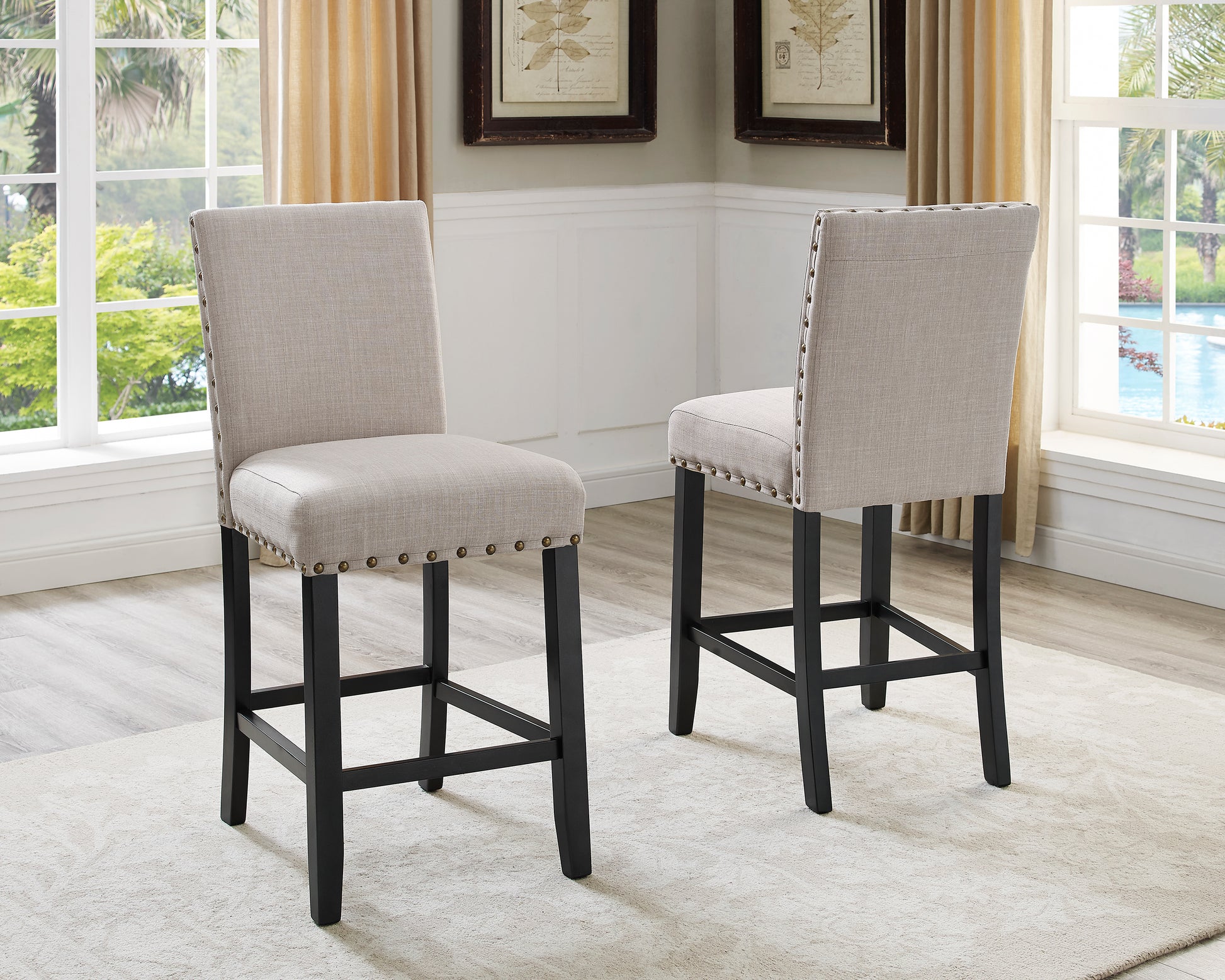 Beige upholstered counter stool with brass nailhead trim and dark wood legs