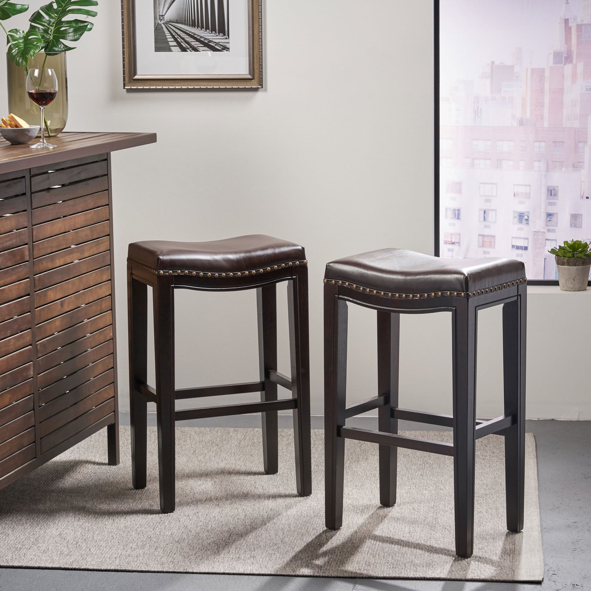 Dark brown leather saddle bar stool with brass nailhead trim and wooden legs