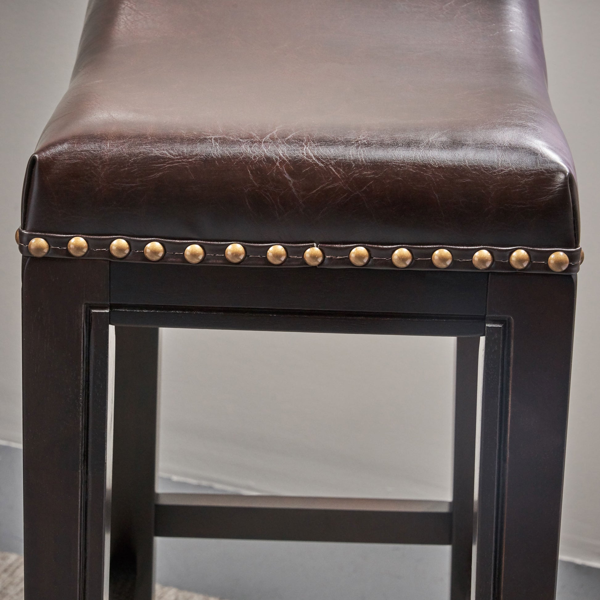 Dark brown faux leather bar stool with brass nailhead trim