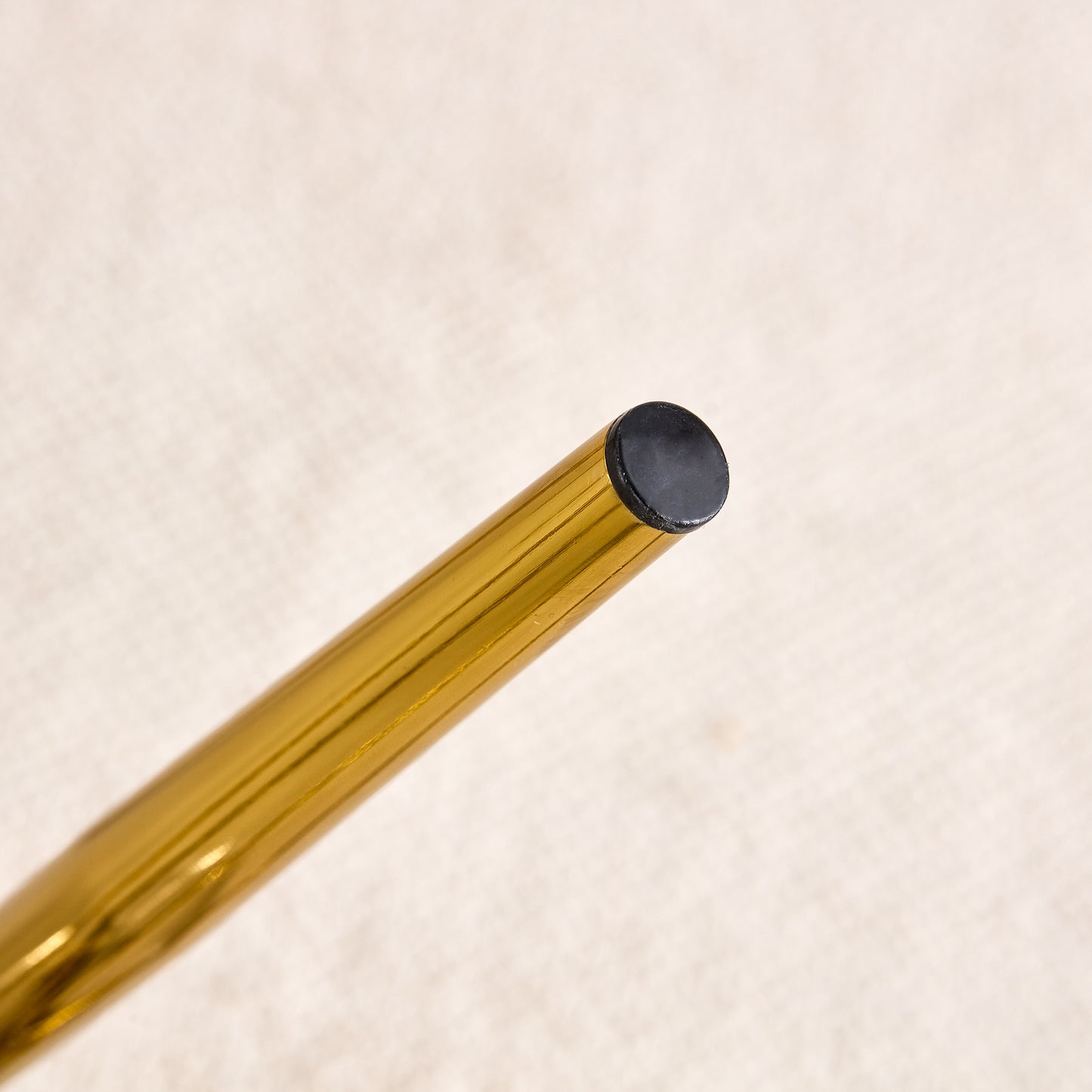 Closeup of a gold metal furniture leg with a black protective cap