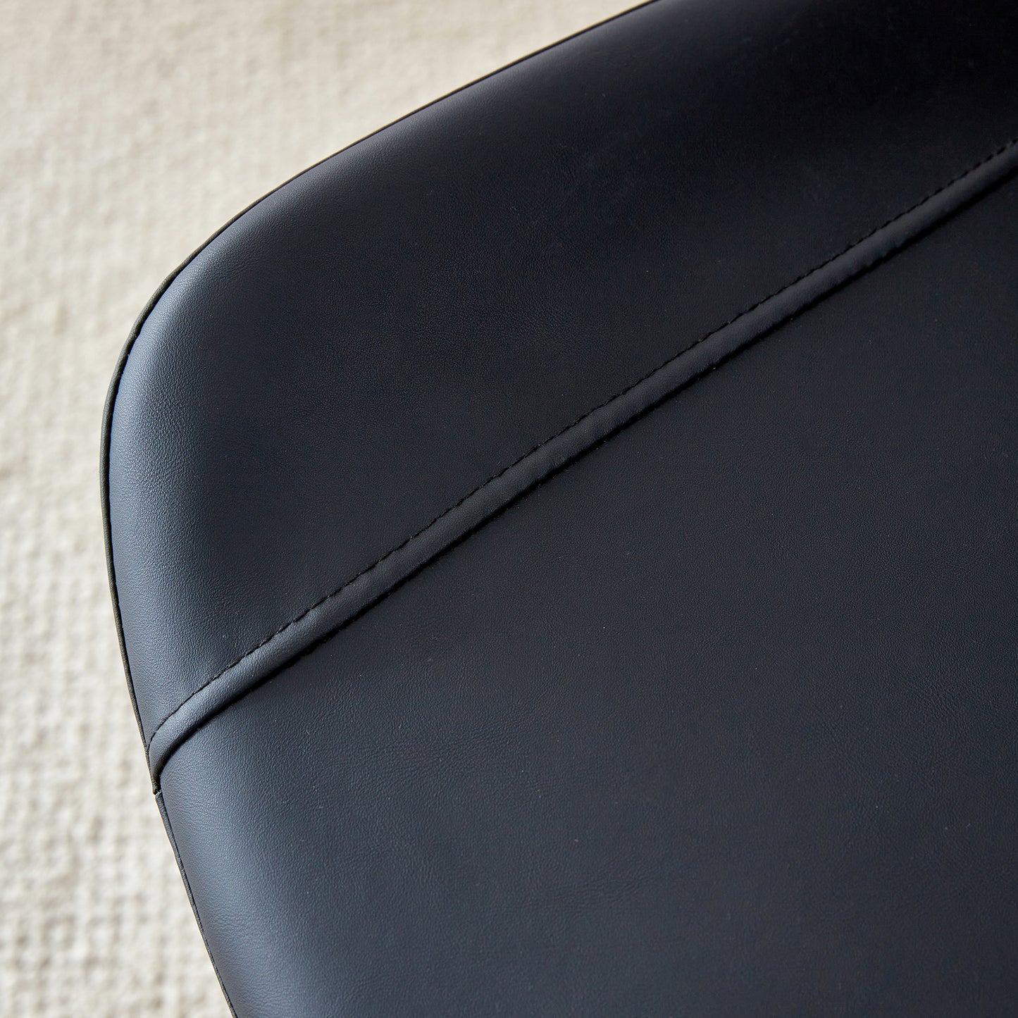 Black leather chair seat detail with visible stitching