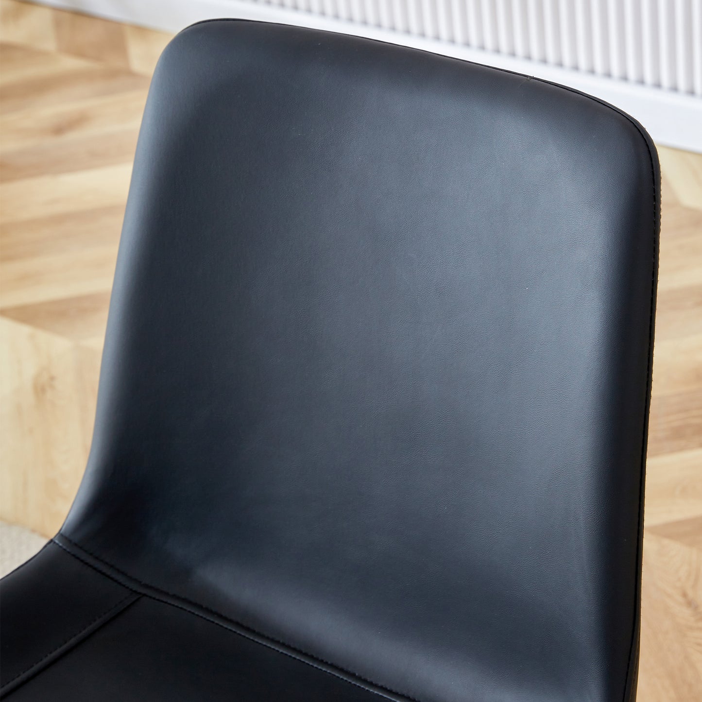 Closeup of a black faux leather chair back with subtle texture