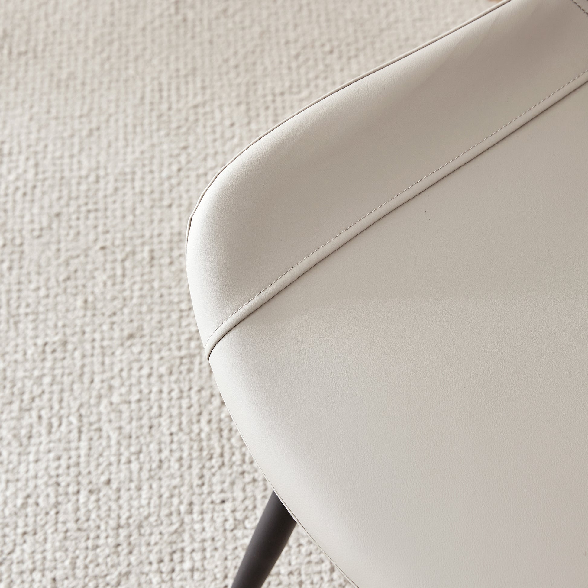 Closeup of cream faux leather chair seat with visible stitching