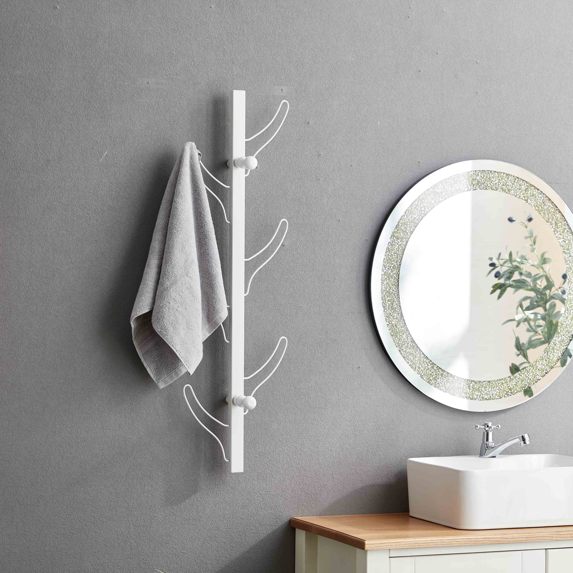 White modern coat rack with curved hooks hanging a grey towel